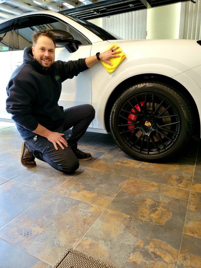 A man is cleaning the tire of his car.